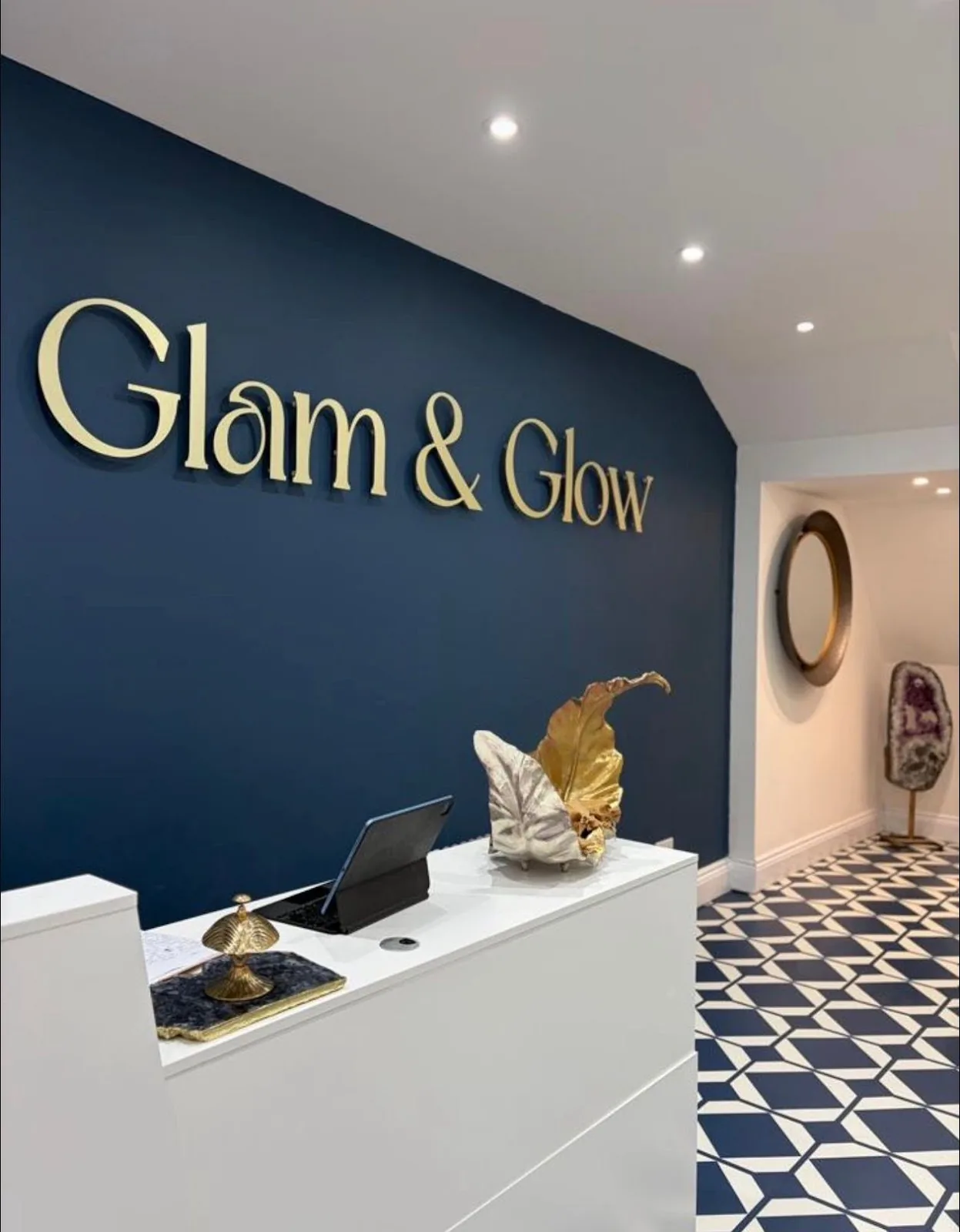 Reception wall of Glam & Glow on Bank Street with gold serif lettering on a deep navy background